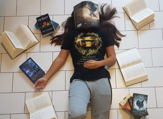 Eine Frau liegt auf dem Boden, ihr Gesicht wird von einem aufgeschlagenen Buch verdeckt. Um sie herum verstreut liegen weitere Bücher.