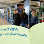 Drei FaMI-Azubinen stehen im Lesesaal der Universitätsbibliothek Erlangen