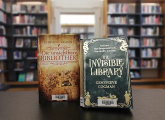 Die englische und die deutsche Ausgabe der "Invisible Library" stehen in einer Bibliothek.