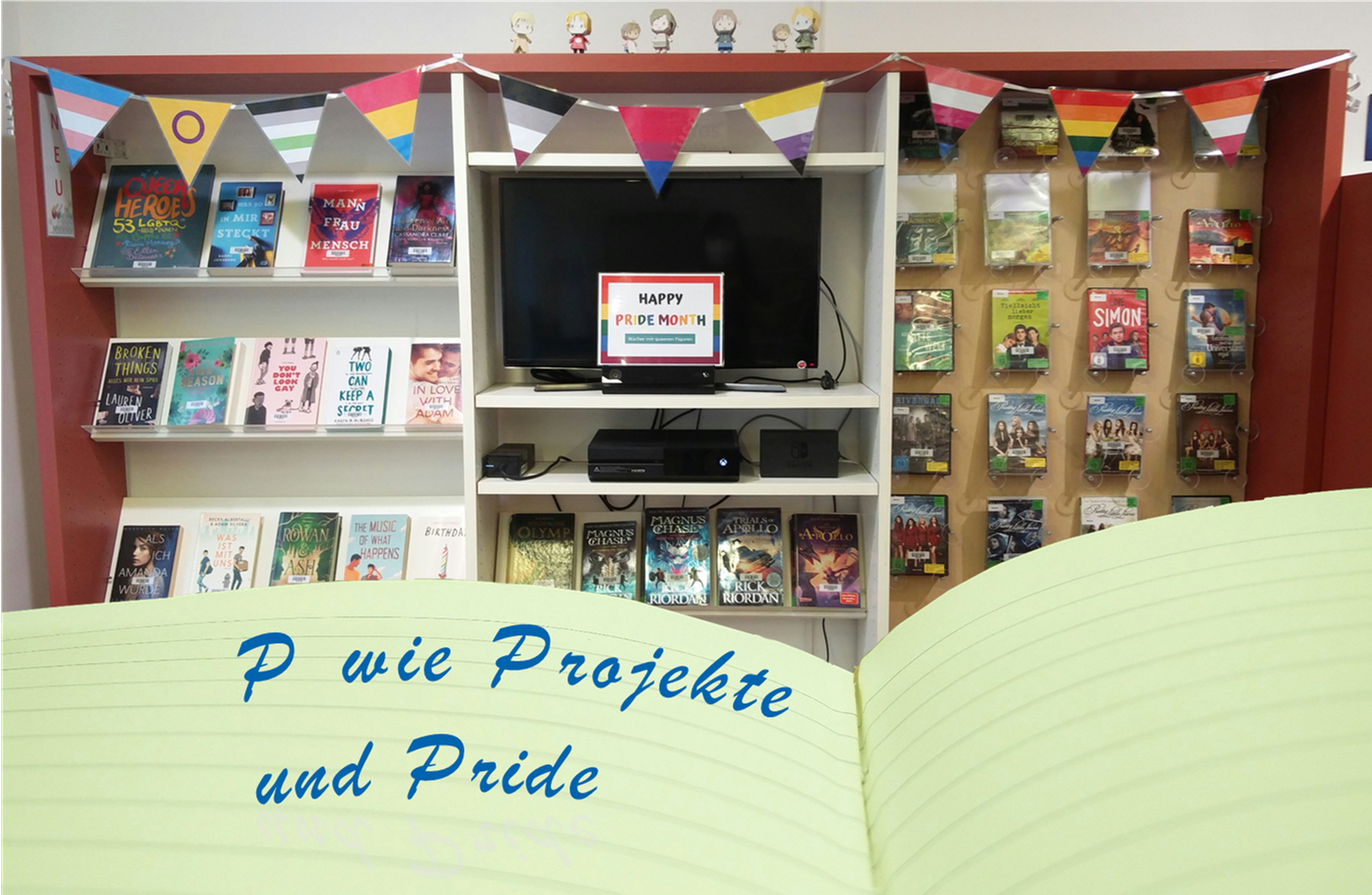 Im Hintergrund ist eine Medienausstellung zum Pride-Month, davor ein aufgeschlagenes Tagebuch mit der Aufschrift "P wie Projekte und Pride". (CC0)