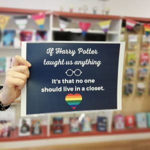 Eine Hand hält ein Schild hoch, auf dem steht: "If Harry Potter taught us anything it's that no one should live in a closet." Im Hintergrund hängen Pride-Flaggen. (CC0)