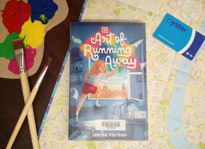 Das Buch "The art of running away" liegt auf einer Karte von London. Daneben liegen eine Oystercard und Pinsel mit Farbe.
