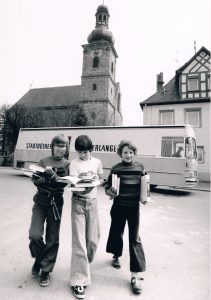 Das Bild zeigt Kinder mit reicher Beute in Frauenaurach vor dem Bücherbus.