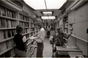 Das Bild zeigt Leser*innen die sich am Bestand der Fahrbibliothek erfreuen.