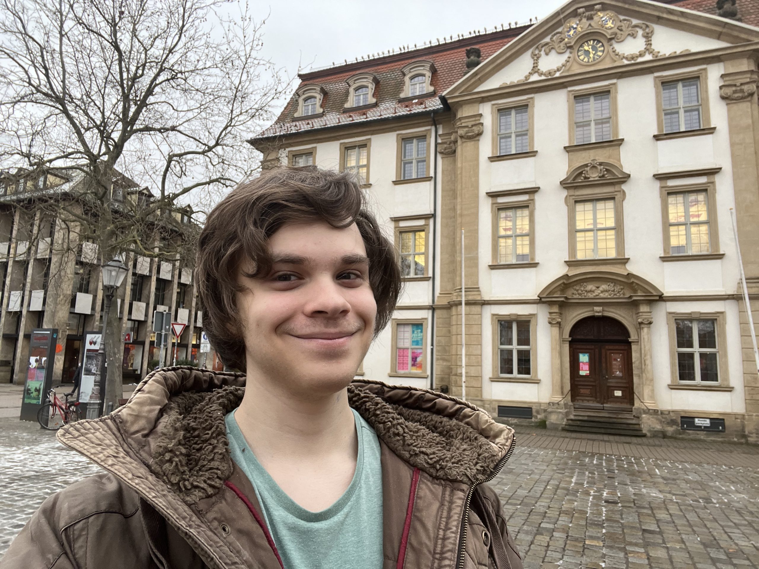Der Praktikant David steht vor der Stadtbibliothek Erlangen.