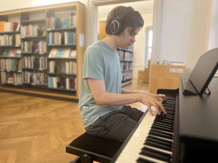 David spielt Klavier in der Musikabteilung der Bibliothek
